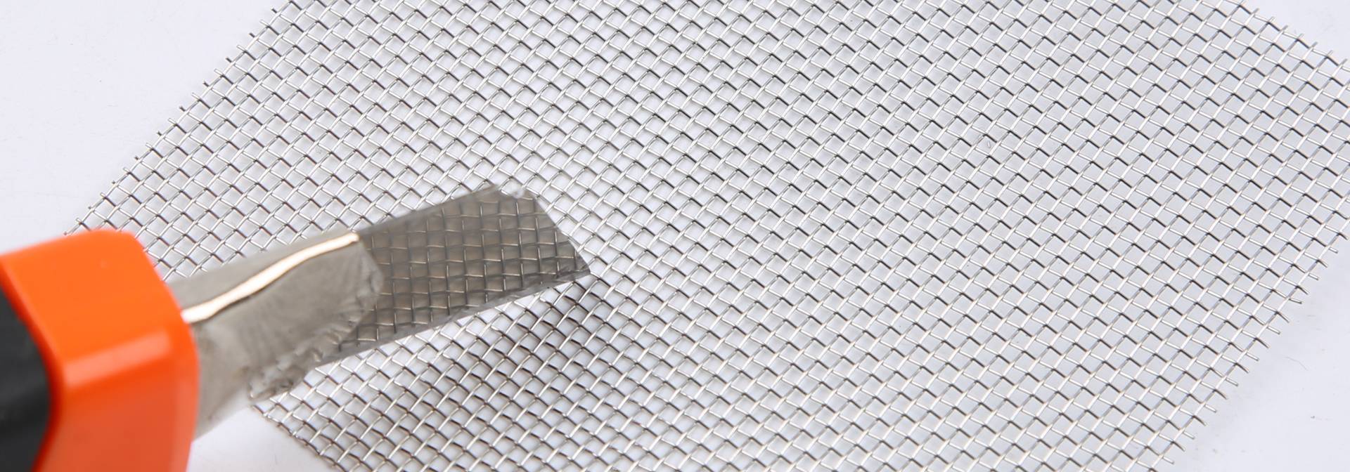 A knife on a sheet of stainless steel window screen mesh.